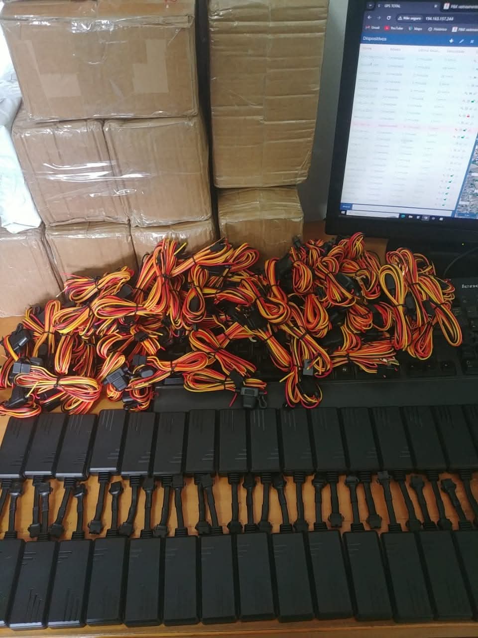 pilha de caixas de papelão embrulhadas em plástico, muitos cabos com fios vermelho/amarelo/laranja emaranhados